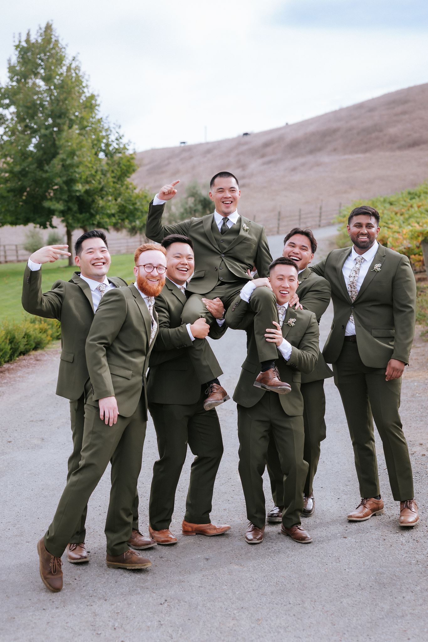 Groomsmen lifting groom up in the air for a celebratory photo at Nella Terra in Sunol