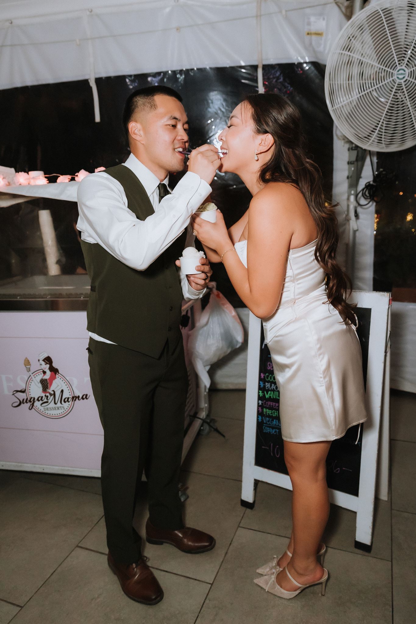 Bride and groom eating ice cream at an ice cream cart at their wedding reception