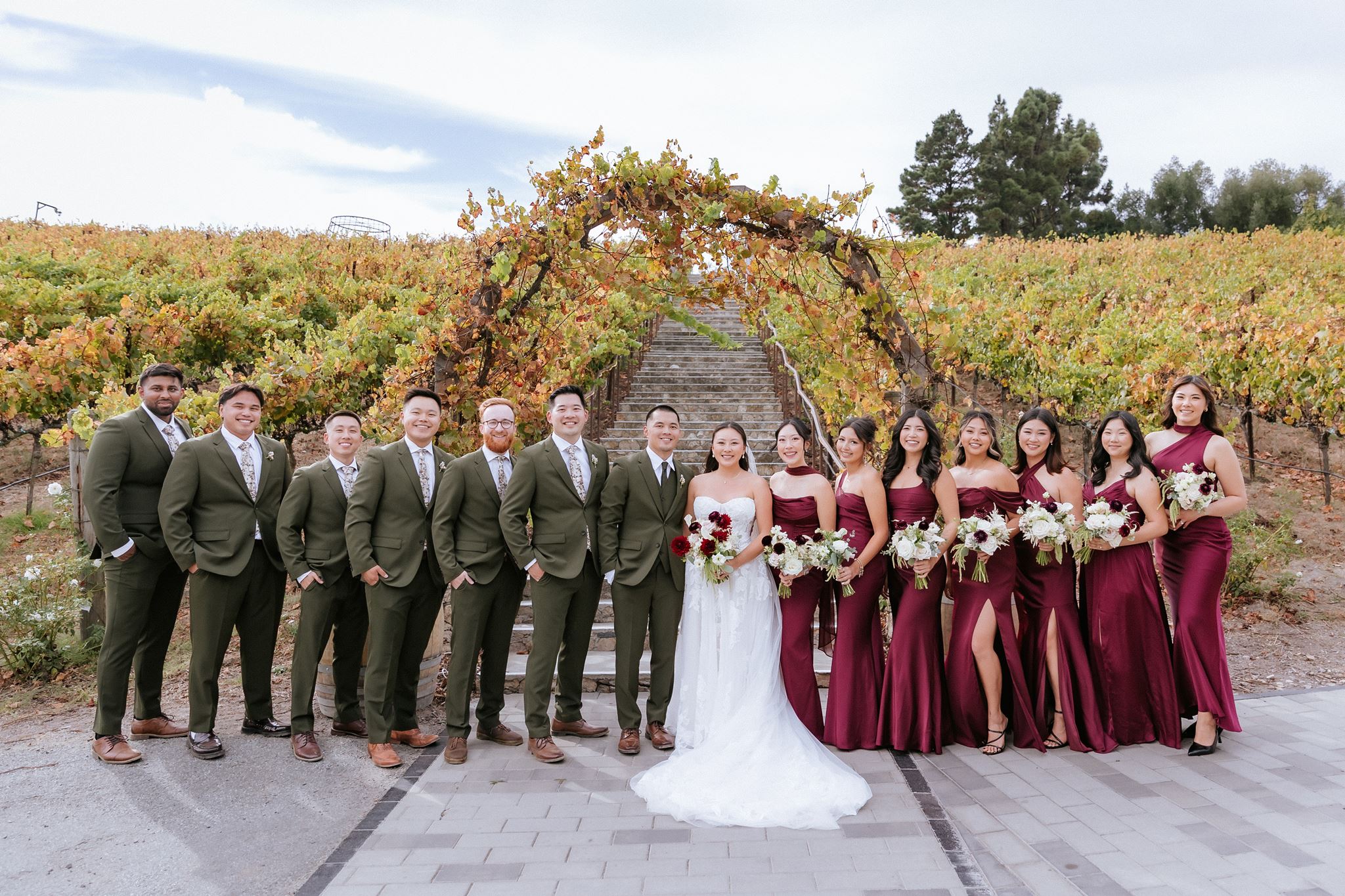 Wedding party with newlyweds posing for formal portrait in the vineyard at Nella Terra